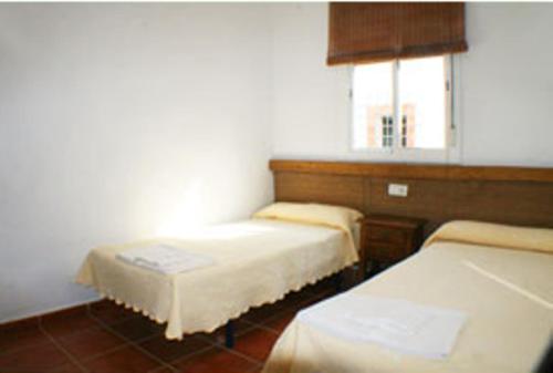 a room with two beds and a window at Apartamentos La Palmera in Conil de la Frontera