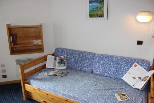 a room with a blue couch with books on it at Temples du Soleil Machu Appartements VTI in Val Thorens