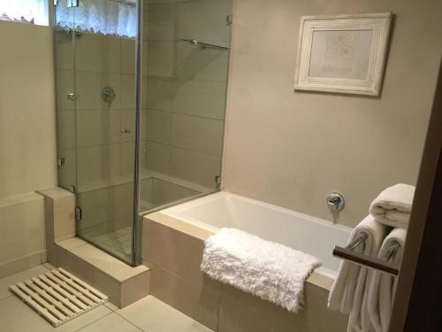 a bathroom with a shower and a bath tub at Plettenberg Bay Getaway in Plettenberg Bay