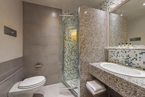 a bathroom with a toilet and a sink and a shower at Hotel Eden in Sirmione