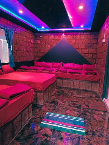 a room with red beds and purple lights at Dandeli redstone cottages in Dandeli