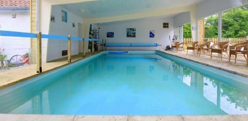 a large swimming pool with blue water and chairs at Les Roulottes des Songes de l'Authie in Boufflers