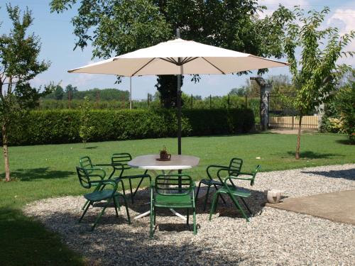 stół i krzesła z parasolem na dziedzińcu w obiekcie Cascina la Barona w mieście Savigliano