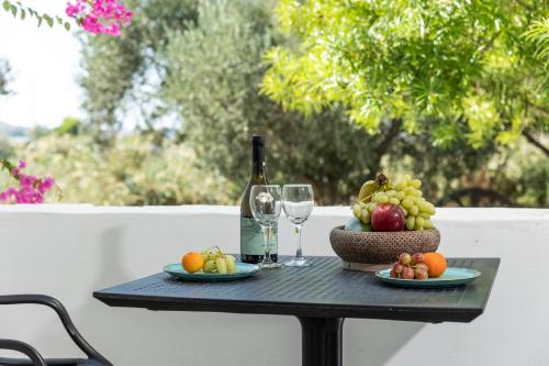 una mesa con una botella de vino y una cesta de fruta en Helios Beach Studios, en Plaka