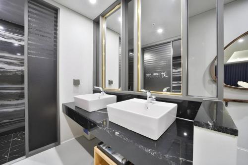 two white sinks in a bathroom with mirrors at Hotel PIED Suseong in Uksu
