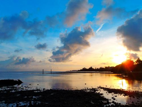 a sunset over a body of water with the sun setting at Life is a Journey in Yomitan