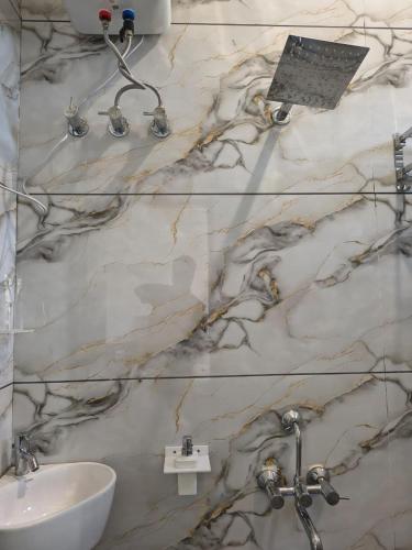 a bathroom with a marble wall with a sink at Shree Vallabh Resort in Nāthdwāra