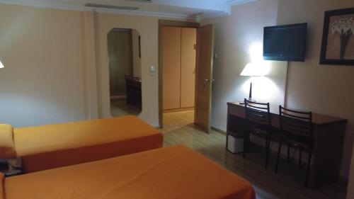 a hotel room with two beds and a desk at Hotel Cabañas in Puertollano