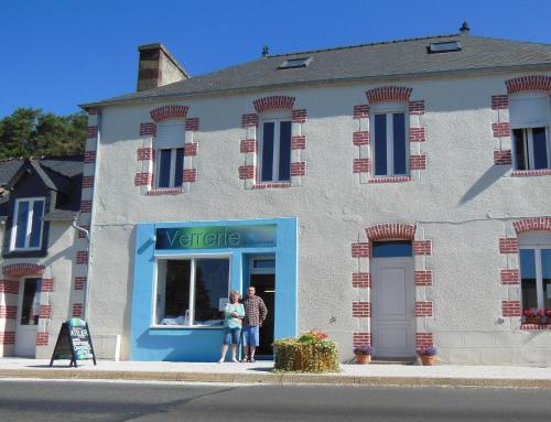 duas pessoas à porta de um edifício em La Verrerie de Guerlédan em Caurel