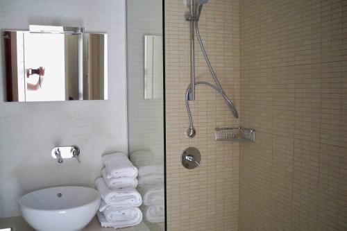 a bathroom with a sink and a shower with towels at Aphrodite Samos Suites in Marathokampos