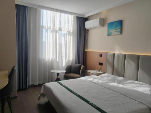 a bedroom with a bed and a chair and a window at GreenTree Inn Suzhou Wujiang Zhenze Town Zhennan Road Express Hotel in Suzhou