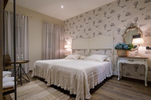 a bedroom with a bed with a white bedspread and a mirror at La Casona de Nené in Arzúa