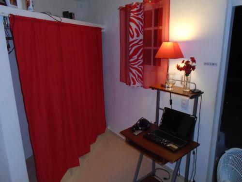a room with a red curtain and a desk with a laptop at Guesthouse Villa La Isla in La Romana