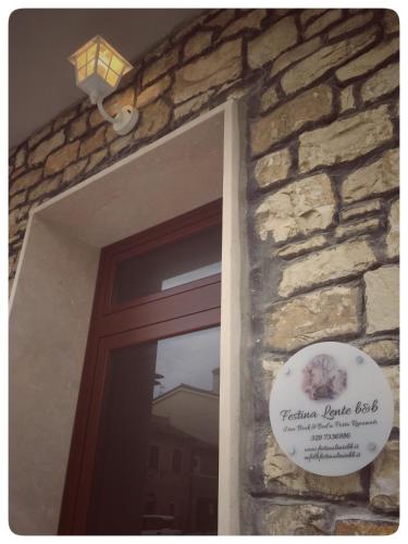 a door with a sign next to a stone wall at Festina Lente B&B in Porto Recanati