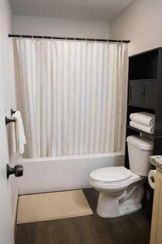 a bathroom with a toilet and a shower curtain at Cozy House in Mayberry in Mission