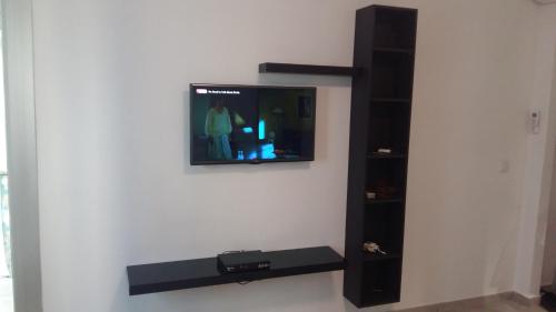 a flat screen tv on a wall with a shelf at Le lagon de Hammamet in Hammamet