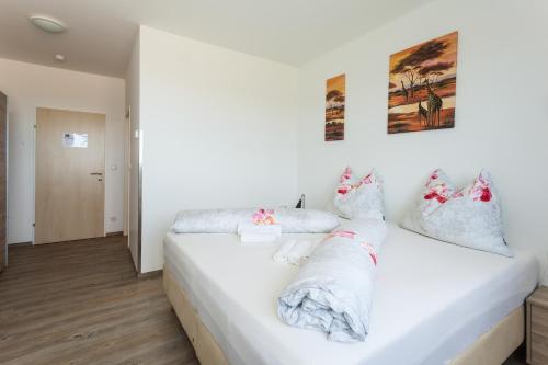 - une chambre avec un lit blanc et des oreillers dans l'établissement Pension Weinbauer, à Hofkirchen im Traunkreis