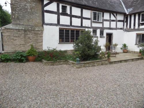 an old white and black house with a gravel driveway at Walford Court in Leintwardine