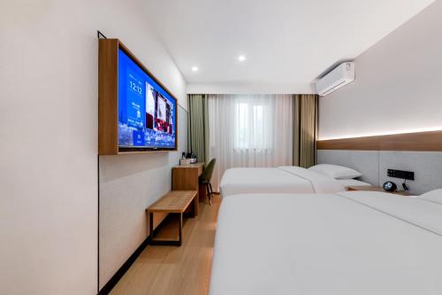 a hotel room with three beds and a flat screen tv at An Yi Hotel in Beijing
