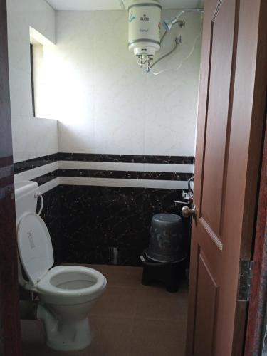 a bathroom with a toilet and a light on the wall at Hotel sai advika in Guirim