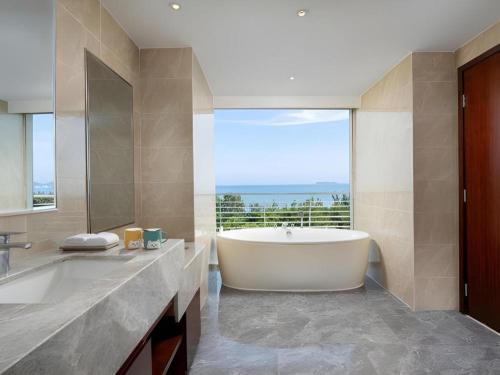 une grande salle de bain avec une baignoire et une grande fenêtre dans l'établissement Grand Soluxe Hotel and Resort Sanya, à Sanya