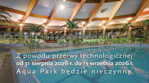 a swimming pool in a building with palm trees at Hotel Warszawianka in Jachranka