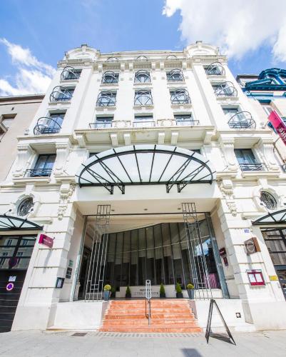 a large white building with a revolving door at Mercure Lille Roubaix Grand Hôtel in Roubaix