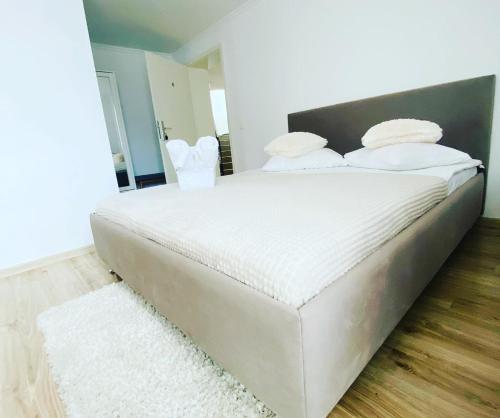 Una cama con sábanas blancas y almohadas en un dormitorio. en Oana Boutique C D I, en Bran