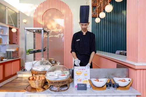 a chef standing in a kitchen with some food at The Sea Cret Hua Hin in Hua Hin