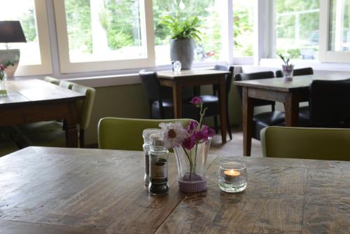 a table with a vase of flowers and candles on it at Hotel Molengroet in Noord-Scharwoude