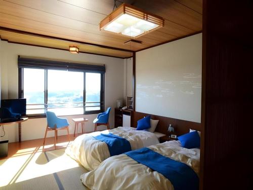 a bedroom with two beds and a large window at Ikadasou Sanjou in Matoya
