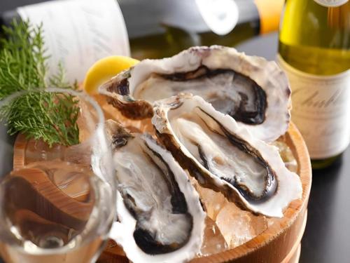 three oysters in a basket next to a bottle of wine at Ikadasou Sanjou in Matoya