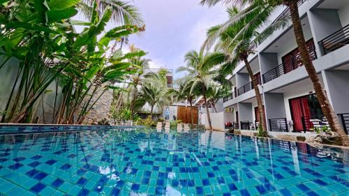 a large swimming pool in a hotel with palm trees at Baan Phu Chalong Place in Ban Suan