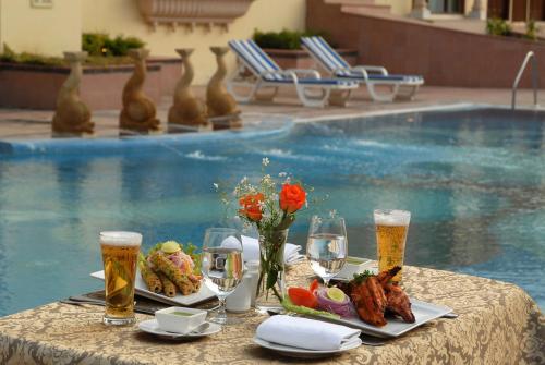 a table with plates of food and glasses of beer at Rajasthali Resort & Spa in Jaipur