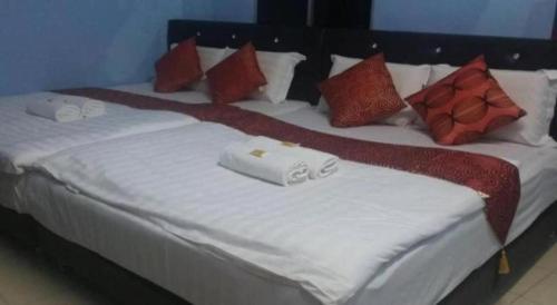 1 cama grande con sábanas blancas y almohadas rojas en Mawanza Motel, en Langkawi Islands
