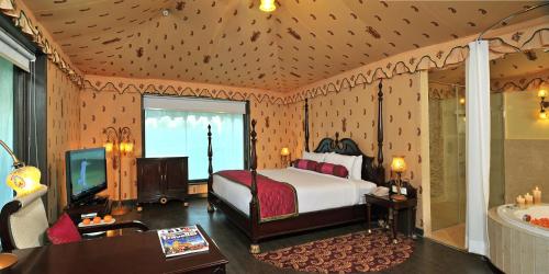 a bedroom with a bed and a tv and a tub at Rajasthali Resort & Spa in Jaipur