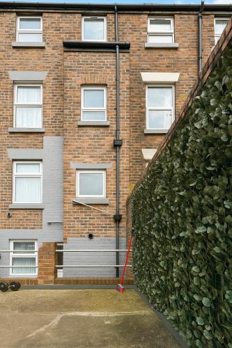 a brick building with a green hedge in front of it at Sidemersey Livings - Botanical Hidden Gems, Magical Gardens in Liverpool