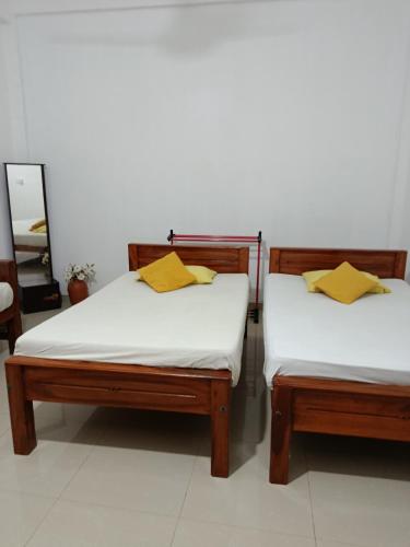 two beds in a room with yellow pillows on them at Wild Safariy in Tissamaharama