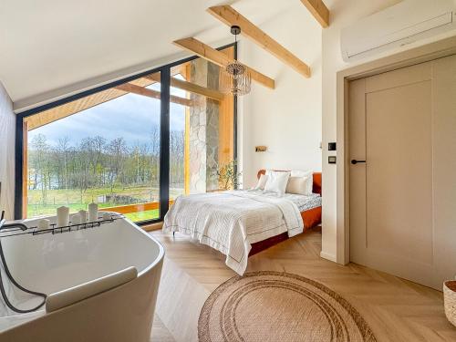 Un dormitorio con bañera y cama y una ventana. en Żurawia Kraina, 