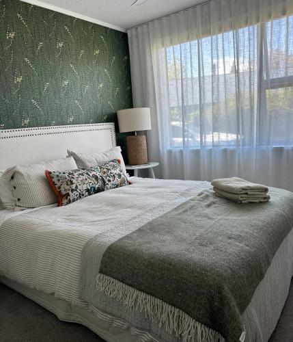 a bedroom with a large bed with a green wall at Omara-more in Omarama