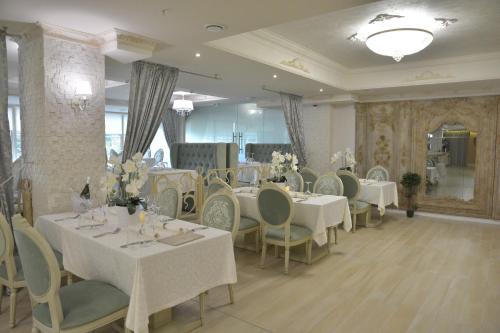 a dining room with white tables and chairs at Bristol Central Park Hotel in Chişinău