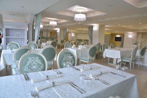 un comedor con mesas y sillas blancas en Bristol Central Park Hotel, en Chişinău