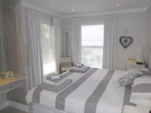 a white bedroom with a large bed and windows at Whale Rock 54 in Hermanus