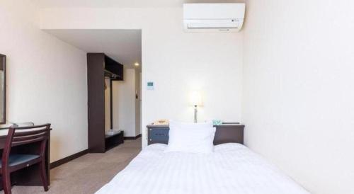 鯖江市にあるTabist Hotel New Osamura Sabaeのベッドルーム1室(白いベッド1台、デスク、椅子付)