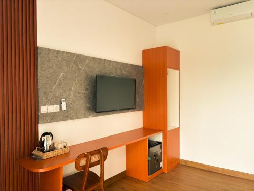 ein Zimmer mit einem Schreibtisch und einem Fernseher an der Wand in der Unterkunft LaVella Villa Jogjakarta kolam renang pribadi in Godean