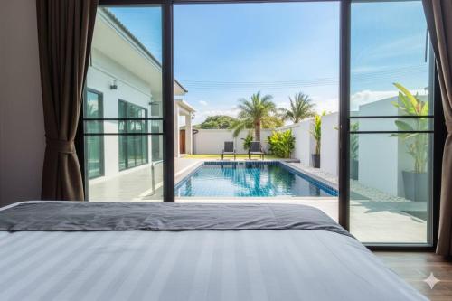 ein Schlafzimmer mit einem Bett und einem Swimmingpool in der Unterkunft Modern pool villa nature and beach Pak Nam Pran - hua hin in Ban Nong Sua