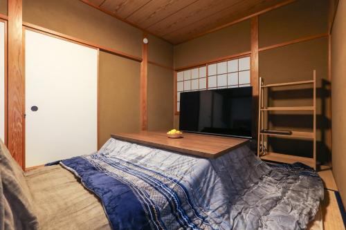 1 dormitorio con 1 cama, TV y estante en 1日1組限定の貸切の民泊です 全館禁煙です 屋外喫煙所無し 間取りは2LDkです 2階部分だけを貸し出してます 1階は立ち入りできません 翌年の3月31日までコタツを設置しています, en Fukui