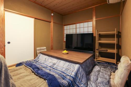 Una sala de estar con una mesa y un televisor. en 1日1組限定の貸切の民泊です 全館禁煙です 屋外喫煙所無し 間取りは2LDkです 2階部分だけを貸し出してます 1階は立ち入りできません 翌年の3月31日までコタツを設置しています, en Fukui