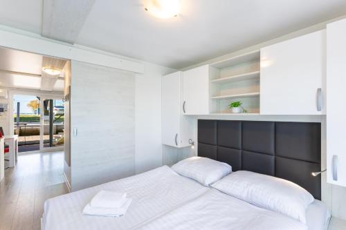 a bedroom with a large white bed with a black headboard at Lovely HouseBoat Apartment Portorose in Portorož