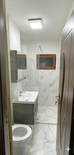 a white bathroom with a toilet and a sink at Tilia Appartment in Craiova
